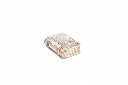 Caixa de comprimidos de prata em forma de livro com gravados nas capas e lombada